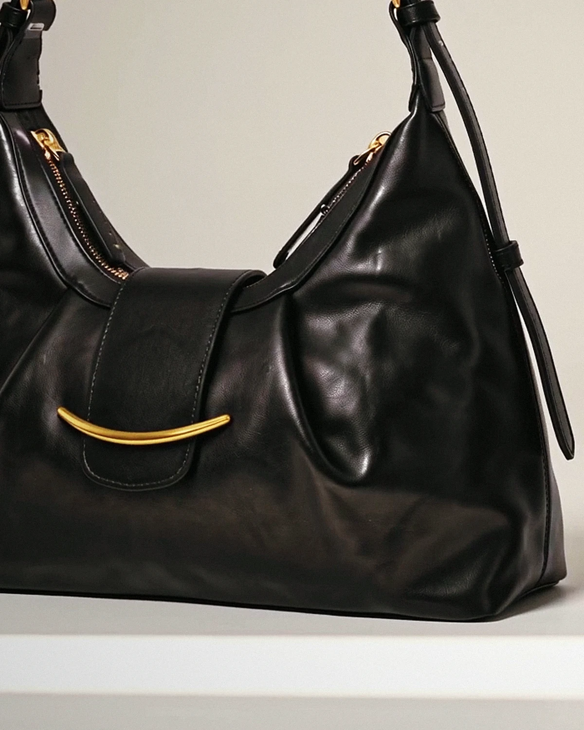Curved gold crescent bar on the large black leather bag